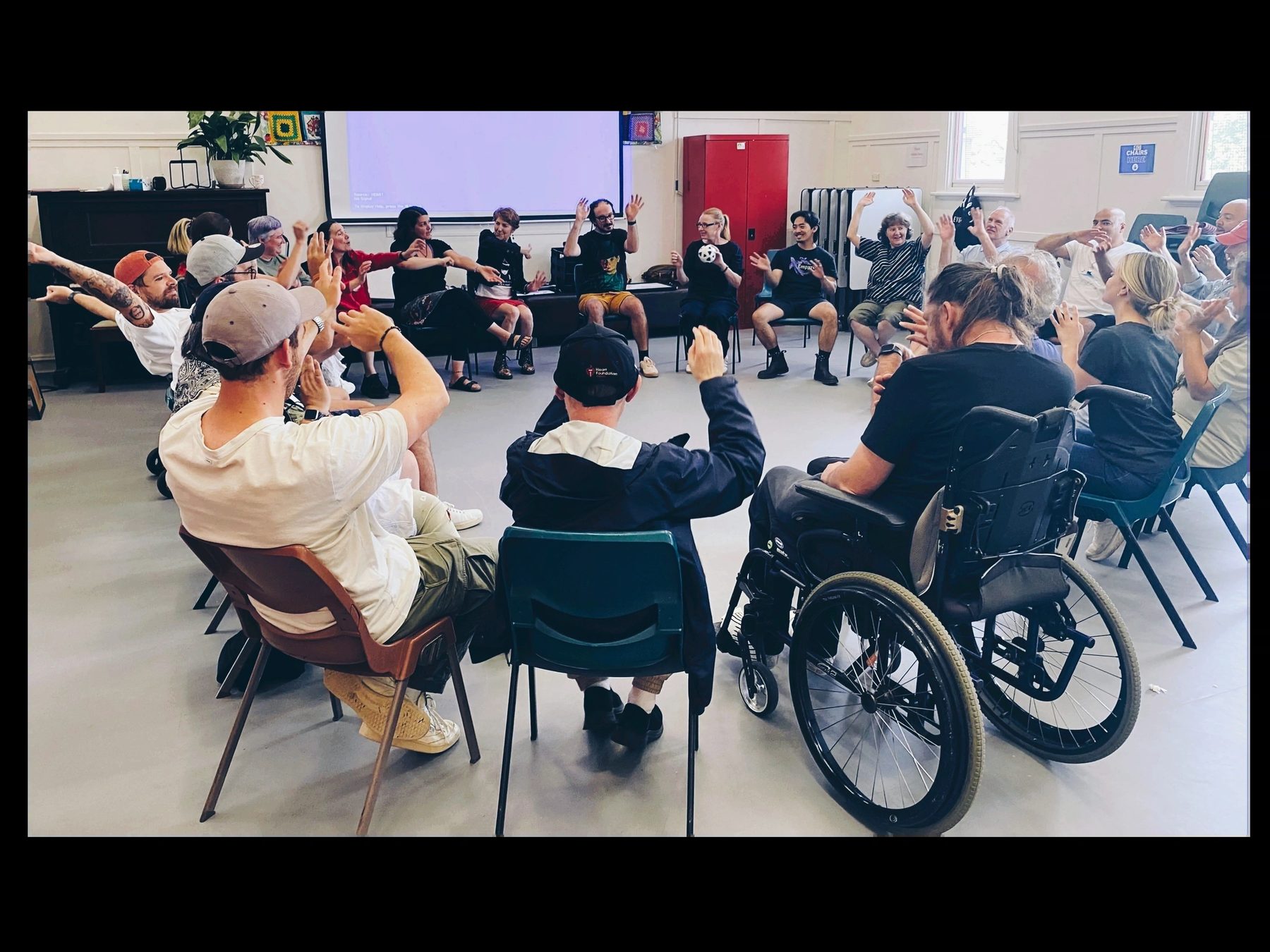 A CUSP group session in a circle, hands raised, everyone smiling
